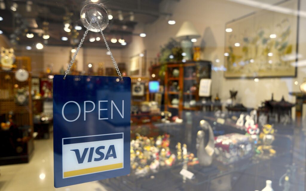 Schild mit Aufschrift "Open Visa" im Schaufenster eines Geschäfts